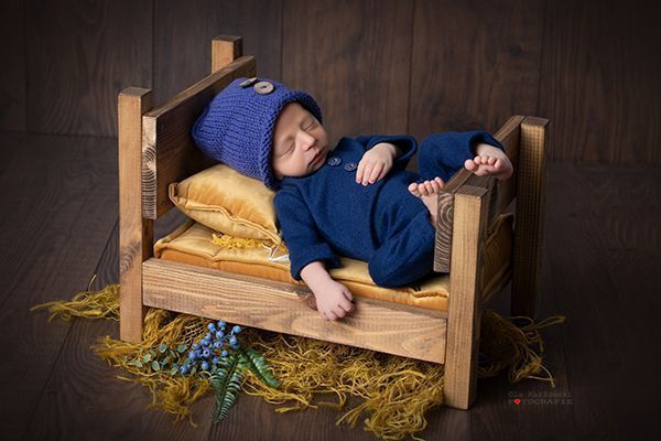 Baby in Holzbett. Schlafend in blauem Schlafanzug. Spezialisitin für Babyfotografie in Düsseldorf. A. Ola Karlowski